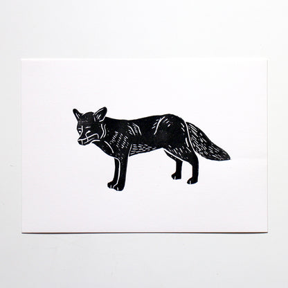 A minimalist black ink illustration of a fox on a white rectangular card, photographed against a light gray background.